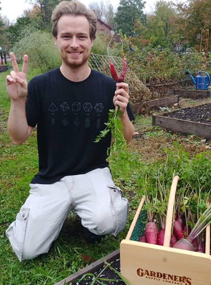 Garden advisor holding vegetable grown in employee gardens