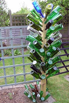 green and blue bottles on a wooden bottle tree