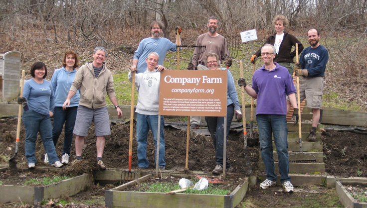 Group of employees gathered around company farm sign