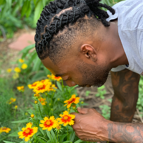Timothy smelling a flower in his garden
