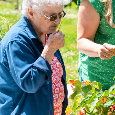  An older woman smelling a leaf