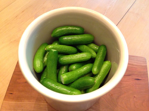 fresh whole cucumbers layered into a pickling crock