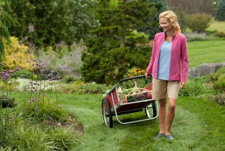 woman pulling garden cart through a perennial garden with lawn pathways