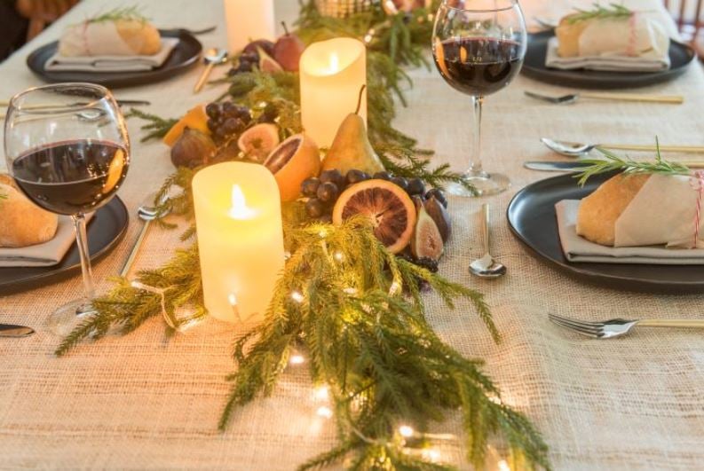 led candles and faux evergreens down the center of a holiday table