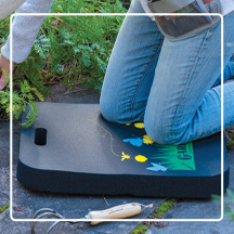 Woman kneeling on Gardener's Kneeling Pad on patio next to garden