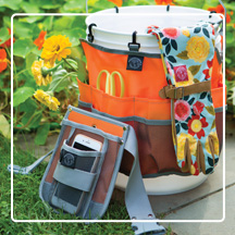 Womenswork Caddy packed with garden gloves and tools in front of garden bed